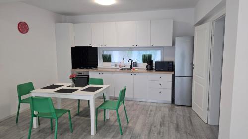 a kitchen with a white table and green chairs at Vila Magurele 2 in Măgurele