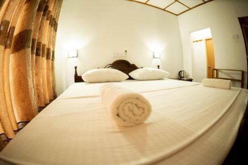 uma cama branca com uma toalha em cima em Nature's peak Udawalawa em Nikawatawana