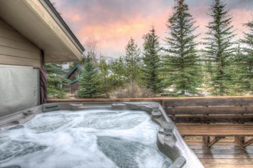 a jacuzzi tub with snow on a deck with trees at Lazy Bear in Breckenridge