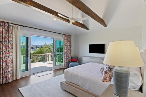 a bedroom with a bed with a lamp and a balcony at SS59: 59 Surfsong in Kiawah Island