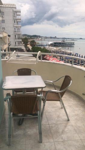 Una mesa y sillas en un balcón con vista al agua. en orange room, en Durrës