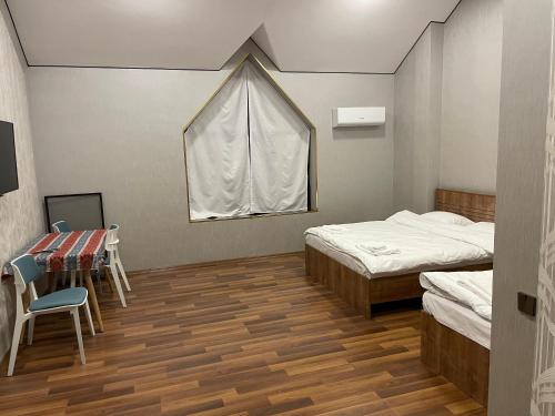 a room with two beds and a table and a window at Malibu hostel pub in Sheki