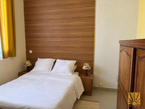 a bedroom with a large bed with a wooden headboard at Golden Sunset - Appart'Hôtel in Antananarivo