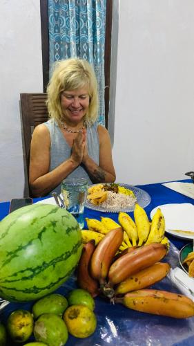a woman sitting at a table with a bunch of fruit at ලෝ LAW Leisure & Wellness Homestay Hostel in Seeduwa