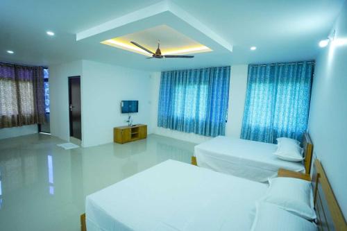 ErumeliにあるHotel O Erumeli Bus Terminal Kottayam Formerly Pious B Residencyのベッド2台と天井ファン付きの寝室