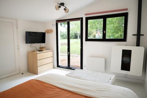 a bedroom with a bed and a flat screen tv at Terrasse, Nature Fontainebleau in Fontaine-le-Port