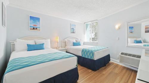 two beds in a room with white walls at Pelican Pointe Clearwater Beach Hotel in Clearwater Beach