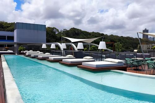 a swimming pool with chaise lounges and chairs on a building at Setai Yacht com Café by Apartamentos Jampa in João Pessoa