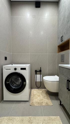 eine Waschmaschine in einem Badezimmer mit Toilette in der Unterkunft DeLuXe CLASS HOME in Almaty