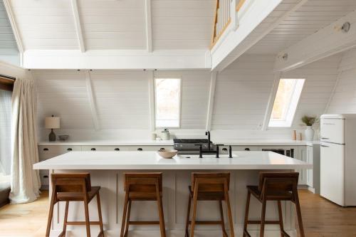 una cocina con una gran isla blanca con taburetes en A-Frame Haus Heber views romantic firepit cute, en Timber Lakes