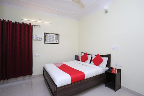 a bedroom with a bed with red and white pillows at Hotel O Lime Wood in Dehradun
