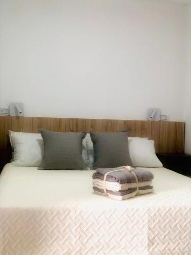- un lit avec des draps et des oreillers blancs dans l'établissement Pen y Gelli, à Puerto Madryn