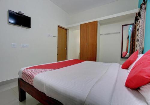 Un dormitorio con una gran cama blanca con almohadas rojas. en Fortune Residency Yercaud, en Yercaud