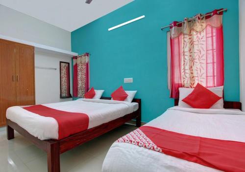 2 camas en una habitación de color azul y rojo en Fortune Residency Yercaud, en Yercaud