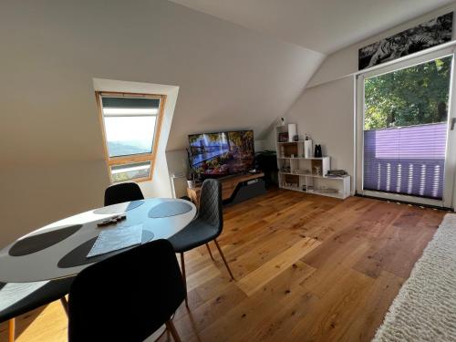 een woonkamer met een tafel, stoelen en een televisie bij Traum Berg - Koppelberg in Traben-Trarbach