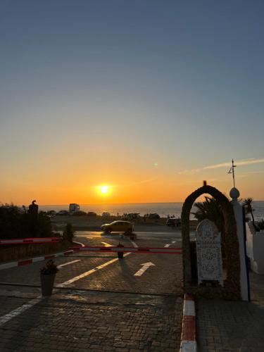 a sunset over a parking lot with a gate at Appartement bord de mer in Jbila