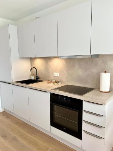 a kitchen with white cabinets and a black dishwasher at Gartenapartment Mariazell in Mariazell