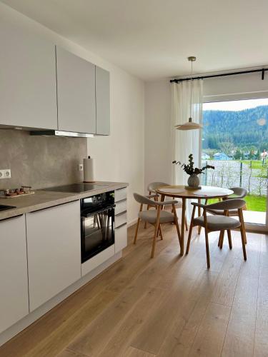 a kitchen with white cabinets and a table with chairs at Gartenapartment Mariazell in Mariazell