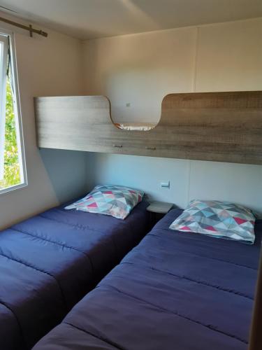 Dos camas en una habitación pequeña con ventana. en Mobil home des gorges de provence, en Montagnac