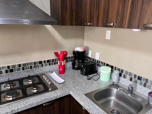 a kitchen counter with a sink and a stove at Centrally located apartment with AC, parking and pool in Guadalajara
