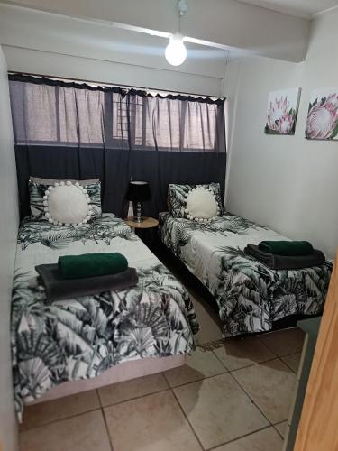 a room with two beds and a table with a lamp at 10 on Cane Street in East London