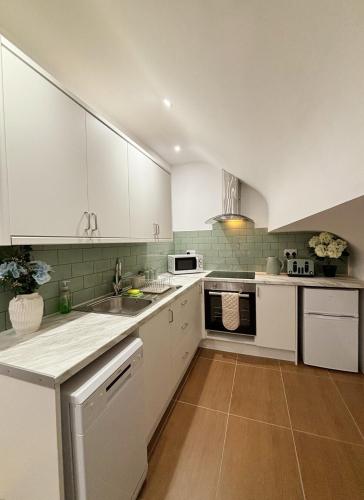 a kitchen with white cabinets and a sink at Welsh Getaway Studio Loft in Merthyr Tydfil
