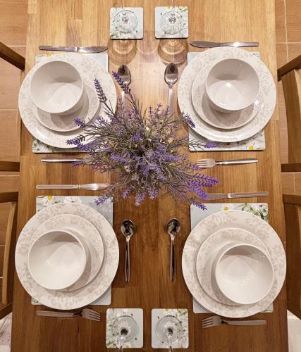 a wooden table with white plates and spoons and flowers at Welsh Getaway Studio Loft in Merthyr Tydfil
