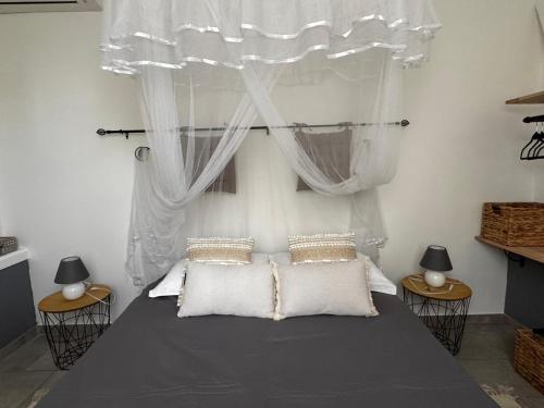 a bedroom with a bed with a canopy and two tables at PAVILLON TI GEMME LE DIAMANT in Le Diamant