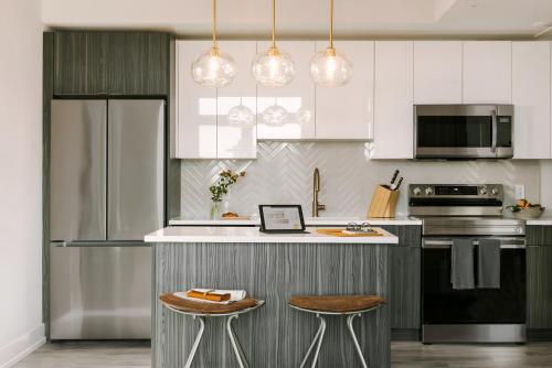 Una cocina con gabinetes blancos y una encimera con taburetes. en Sosuite at The Ovation - Ave of The Arts, en Filadelfia