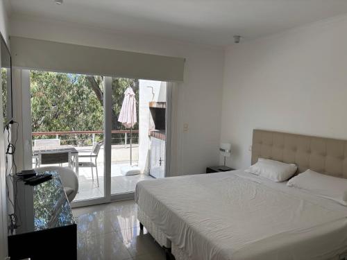 a white bedroom with a bed and a balcony at Green Park Punta 2 in Punta del Este
