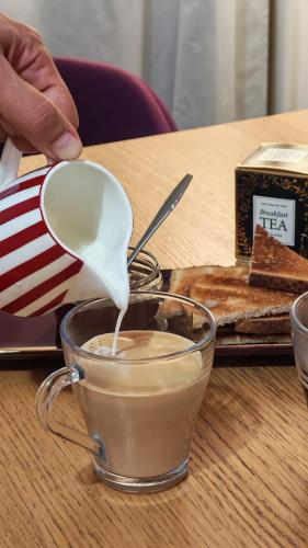 a person is pouring milk into a cup of coffee at LGBTQ-Double room in London