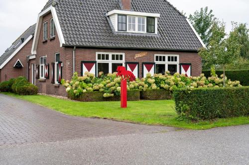 a house with a red statue in the front yard at Bed and Breakfast de Hoge Enk in Hierden