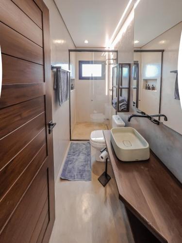 a bathroom with a toilet and a sink and a door at casa mantiqueira in Gonçalves