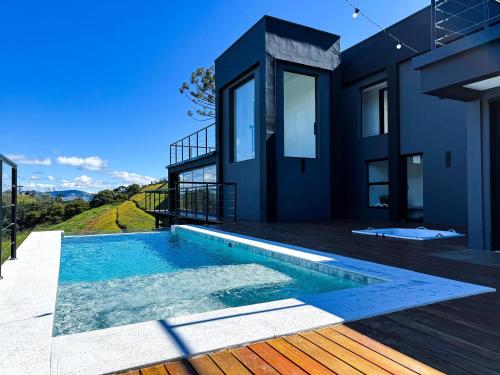 a house with a swimming pool on a deck at casa mantiqueira in Gonçalves