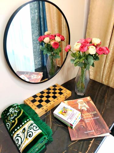 a table with a mirror and flowers and a chessboard at Апартаменты рядом с LRT, Ботаническим садом, EXPO и Barys Arena in Astana