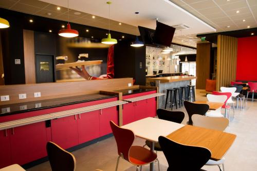 a restaurant with red cabinets and tables and chairs at Transamerica Fit Aracruz in Aracruz