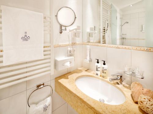 a white bathroom with a sink and a mirror at Familienhotel Hinteregger in Katschberghöhe