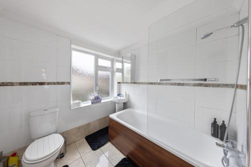 a white bathroom with a tub and a toilet at Lesley House 4 bed villa TV Internet Garden in Gillingham