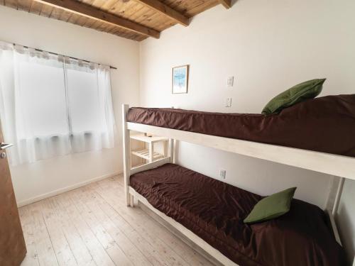 two bunk beds in a room with a window at Casa Joha - Casa en Chapa a 1 cuadra de Luna Roja para 4 PAX - Hola Sur in Chapadmalal