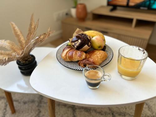 - une table avec un plateau de viennoiseries et un verre de jus d'orange dans l'établissement Appartement proche Ancenis - Loire et Vélo, à Liré