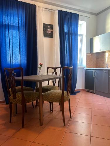 comedor con mesa, sillas y cortinas azules en Blue May Plaza, en Bratislava