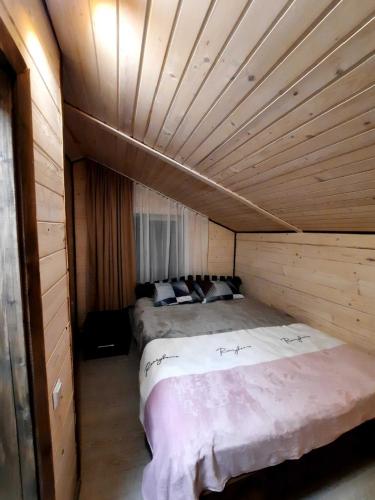 a bedroom with two beds in a wooden room at Подих Карпат in Volosyanka