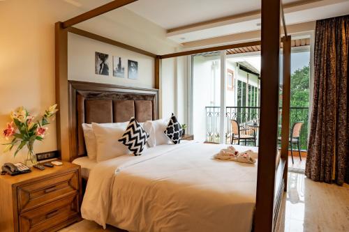 a bedroom with a large bed and a balcony at The Tanisi Resorts & Pool Villas, Candolim in Candolim