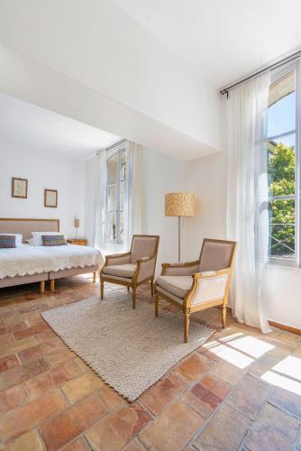 a bedroom with two chairs and a bed and a window at La Prévôté - Luxury Chambres d'hôtes & Gastronomic Restaurant in L'Isle-sur-la-Sorgue
