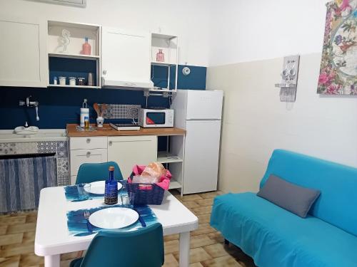 a living room with a table and a blue couch at Mare Sole Vento 38 Punta Prosciutto in Torre Colimena