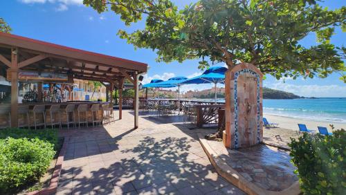 a restaurant on the beach with a tree and chairs at Oceans at Divi Little Bay in Philipsburg