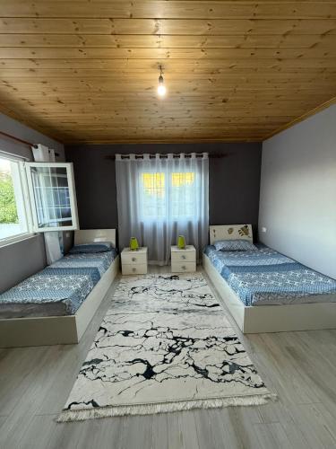 a bedroom with two beds and a rug at Bujtina e Kadrise in Kukës