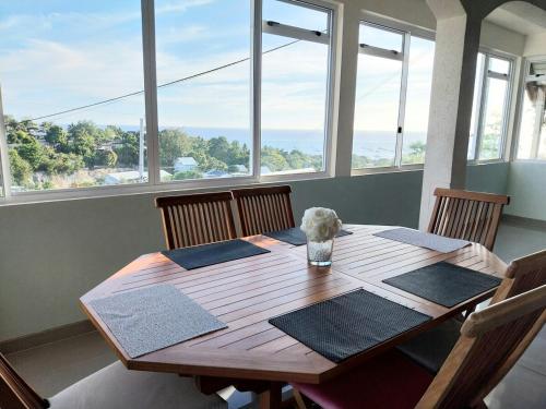 una mesa de madera en una habitación con ventanas en Villa Manuia, à Punaauia, en Punaauia
