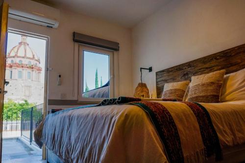 a bedroom with a large bed with a large window at Casa Yuca Hotel in San Miguel de Allende