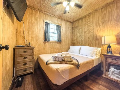 - une chambre avec un lit, une commode et une lampe dans l'établissement Tiny Log Cabin near Fossil Rim | Countryside Views, à Glen Rose